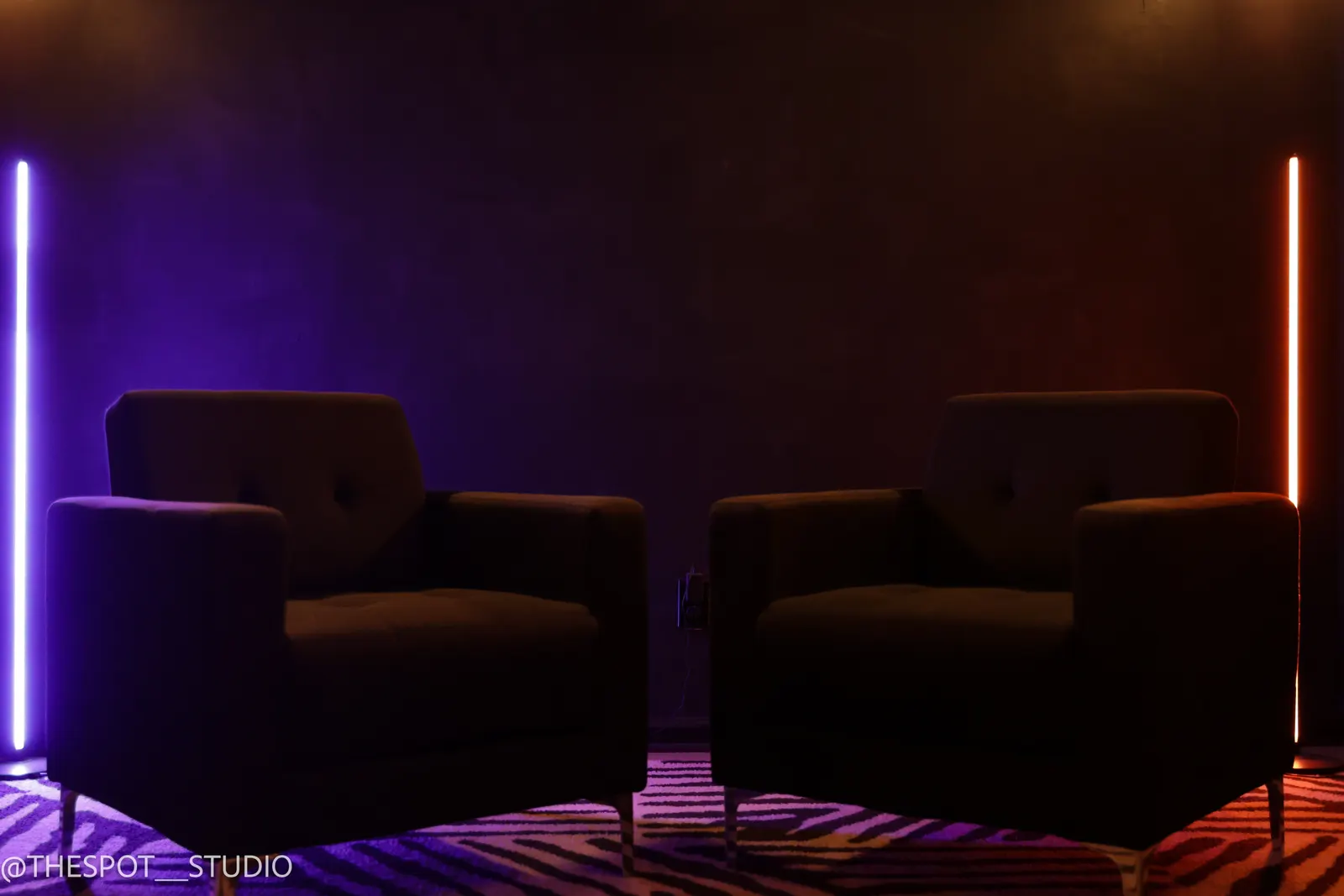 Two armchairs in the Black Room with purple and orange LED light bars